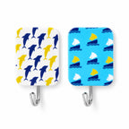 Close-up of two rectangular adhesive hooks, one with yellow and blue dolphins, the other with yellow and white sailboats.