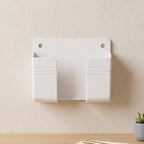 A white wall-mounted phone holder with two compartments on a light brown wall above a wooden desk.