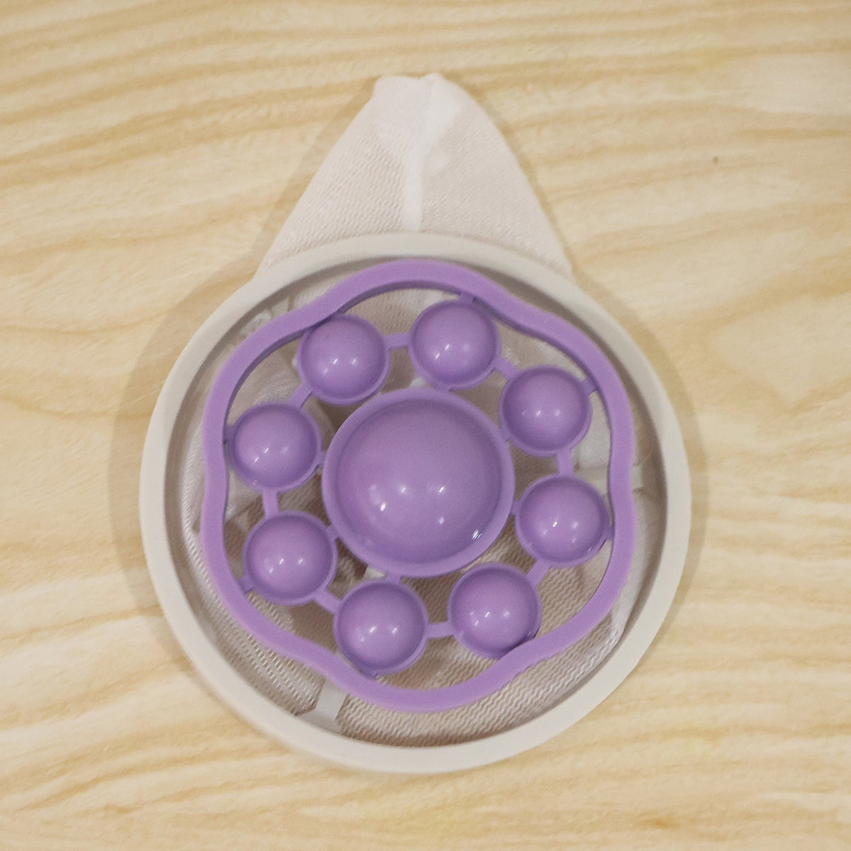 The top view of a purple and white floating lint mesh bag on a light wooden surface.