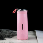 A pink vacuum flask with a silver lid and pink strap sits on a marble surface next to a grey cloth.