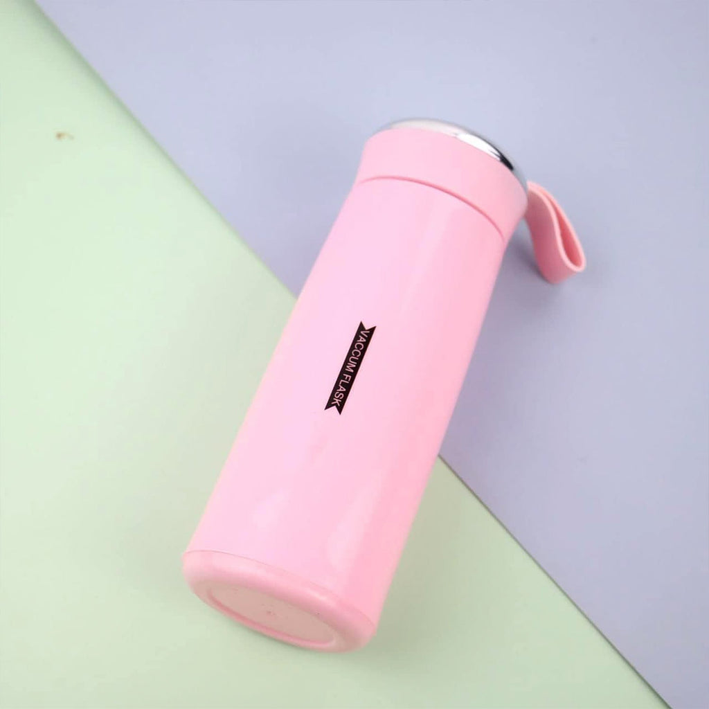 A pink vacuum flask with a silver lid and strap lies diagonally on a light blue and green background.