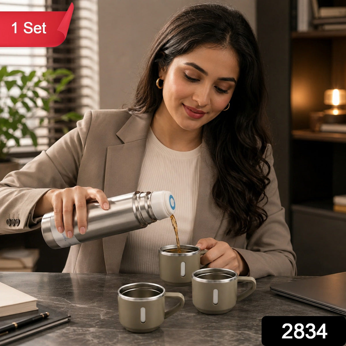 A woman pours coffee from a silver vacuum flask into a beige mug, with two other mugs nearby on a dark desk.