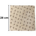 A beige microfiber towel with a dark bow pattern and scalloped edges lies flat on a white background, with a 28 cm