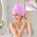 A smiling woman in a white tank top wears a purple microfiber hair wrap, securing it above her ear. 