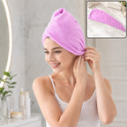 A smiling woman in a white tank top wears a purple microfiber hair wrap, securing it above her ear. 