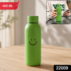 Green glass water bottle with a smiley face on a wooden table, with an inset showing a person holding a similar bottle. The