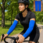 Woman cycling outdoors wearing a black helmet, black shirt, and blue arm sleeves with a logo.