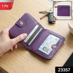 A hand holds an open purple bifold wallet with a credit card and driver's license inside, on a wooden table 